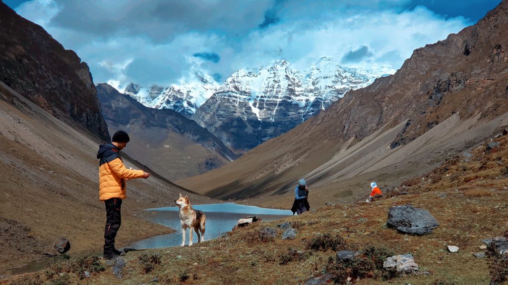 Man feeds a dog near twin lake during Jomolhari trek.